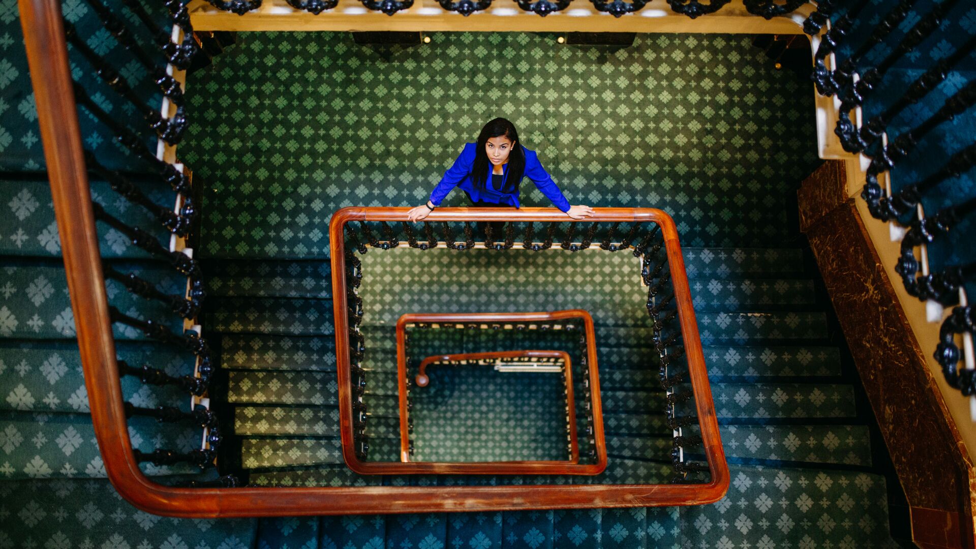 Hull Politics student, Jacqueline Gomes-Neves, stands on a winding staircase in Westminster looking up to the camera.