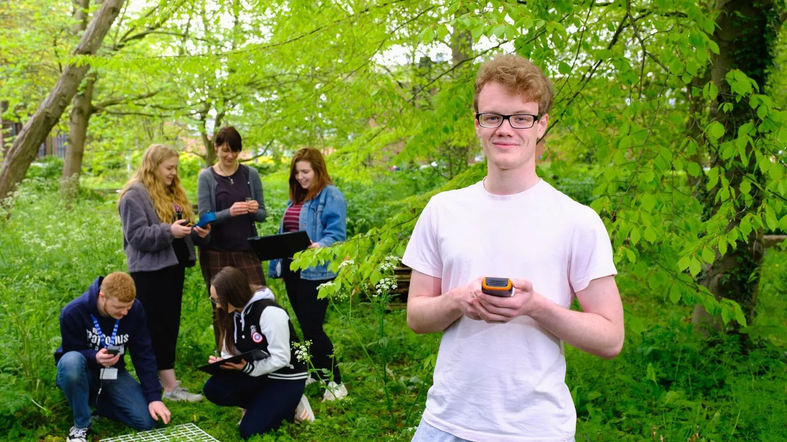 Environmental Science student doing fieldwork in a woodland, with other students in the background