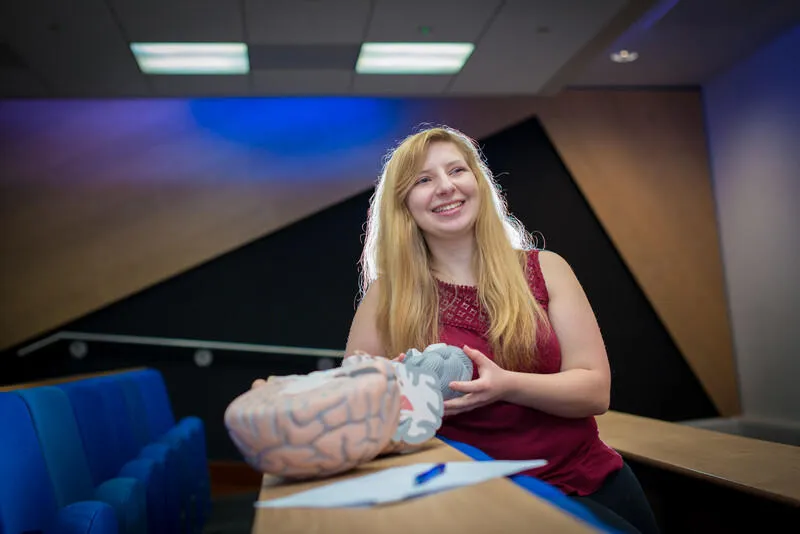 A student sat a table with a model brain