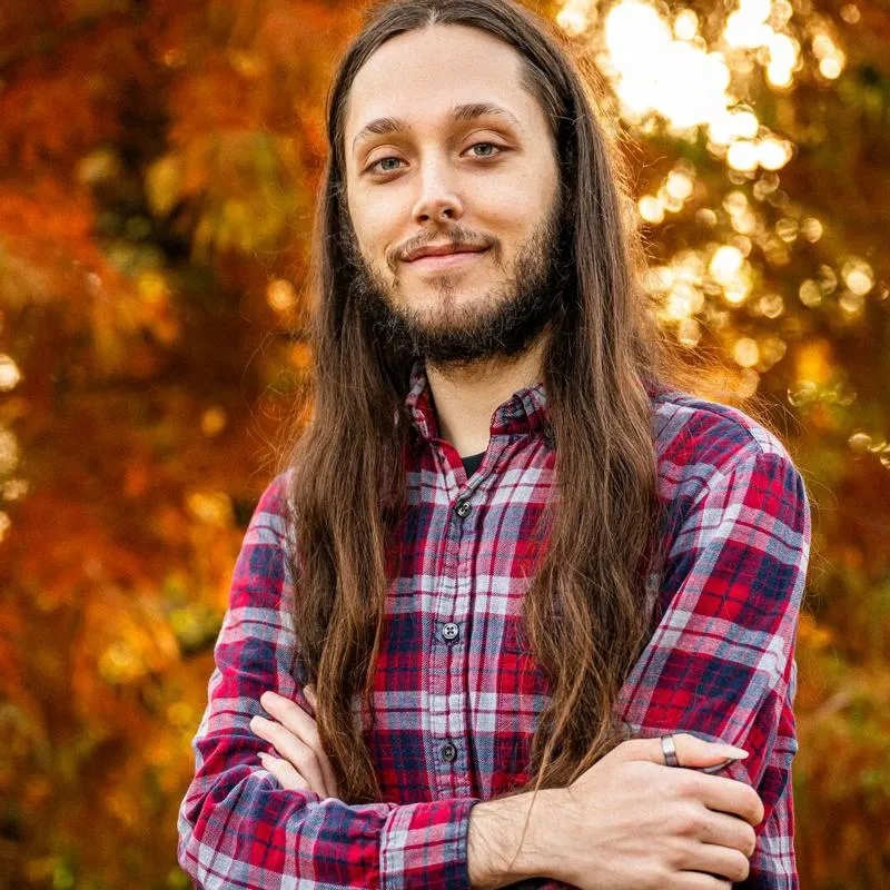 Student in a red checked shirt standing on campus on an autumn day