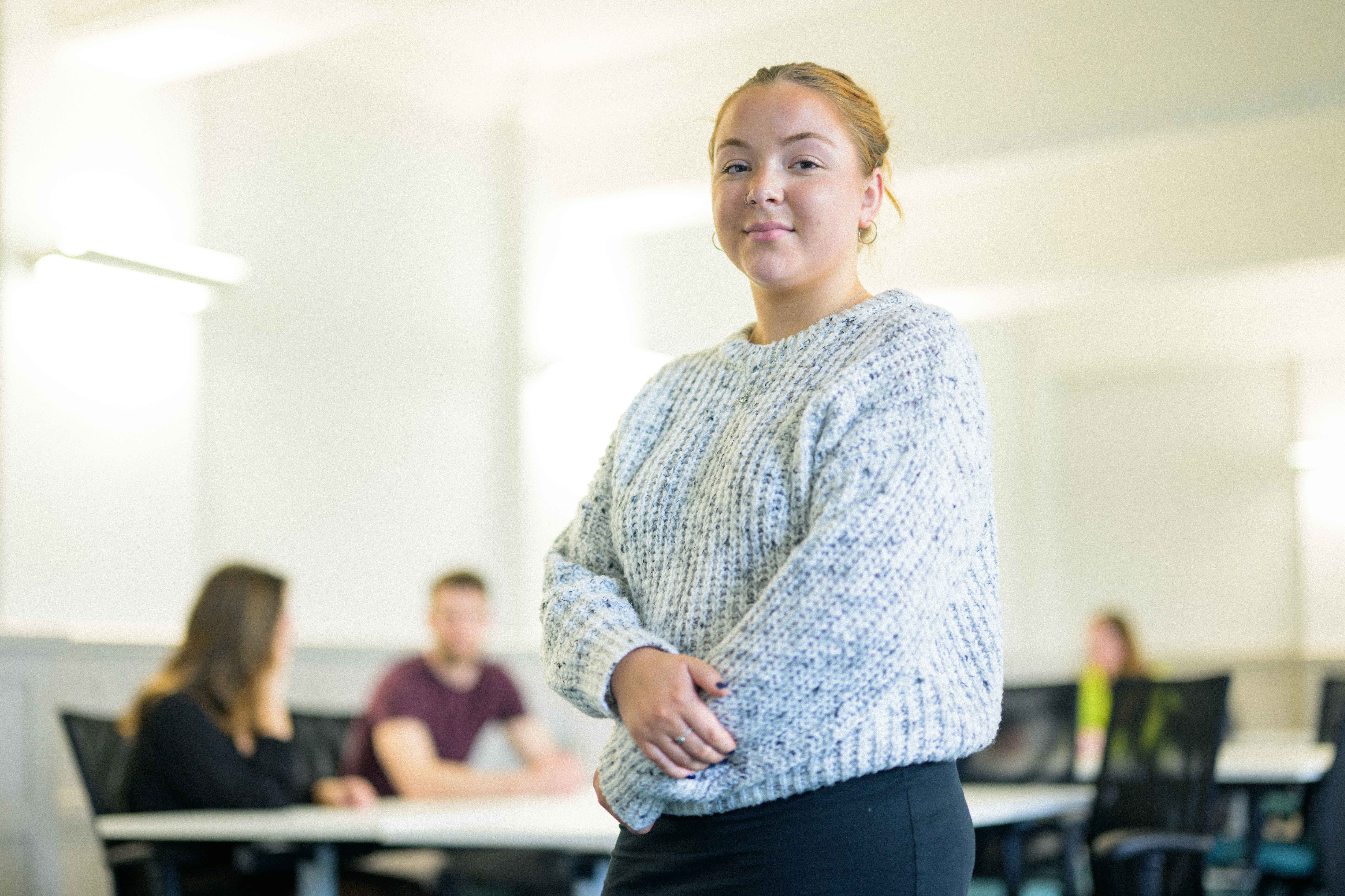 Student stood posing in front of classroom