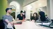 Mixed group laughing over laptops at a table