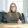 Student sat at desk posing in front of classroom