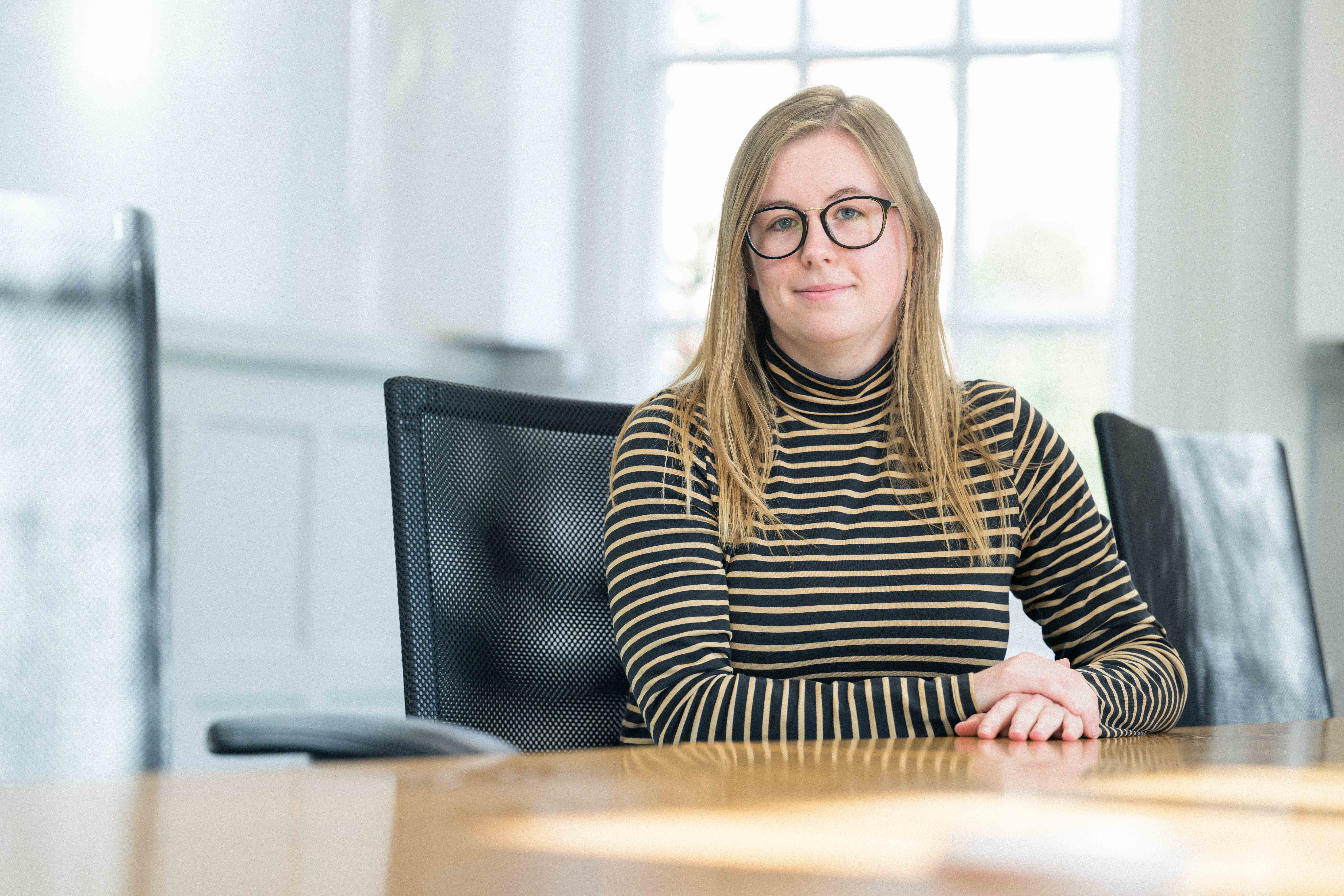Student sat at desk posing in front of classroom