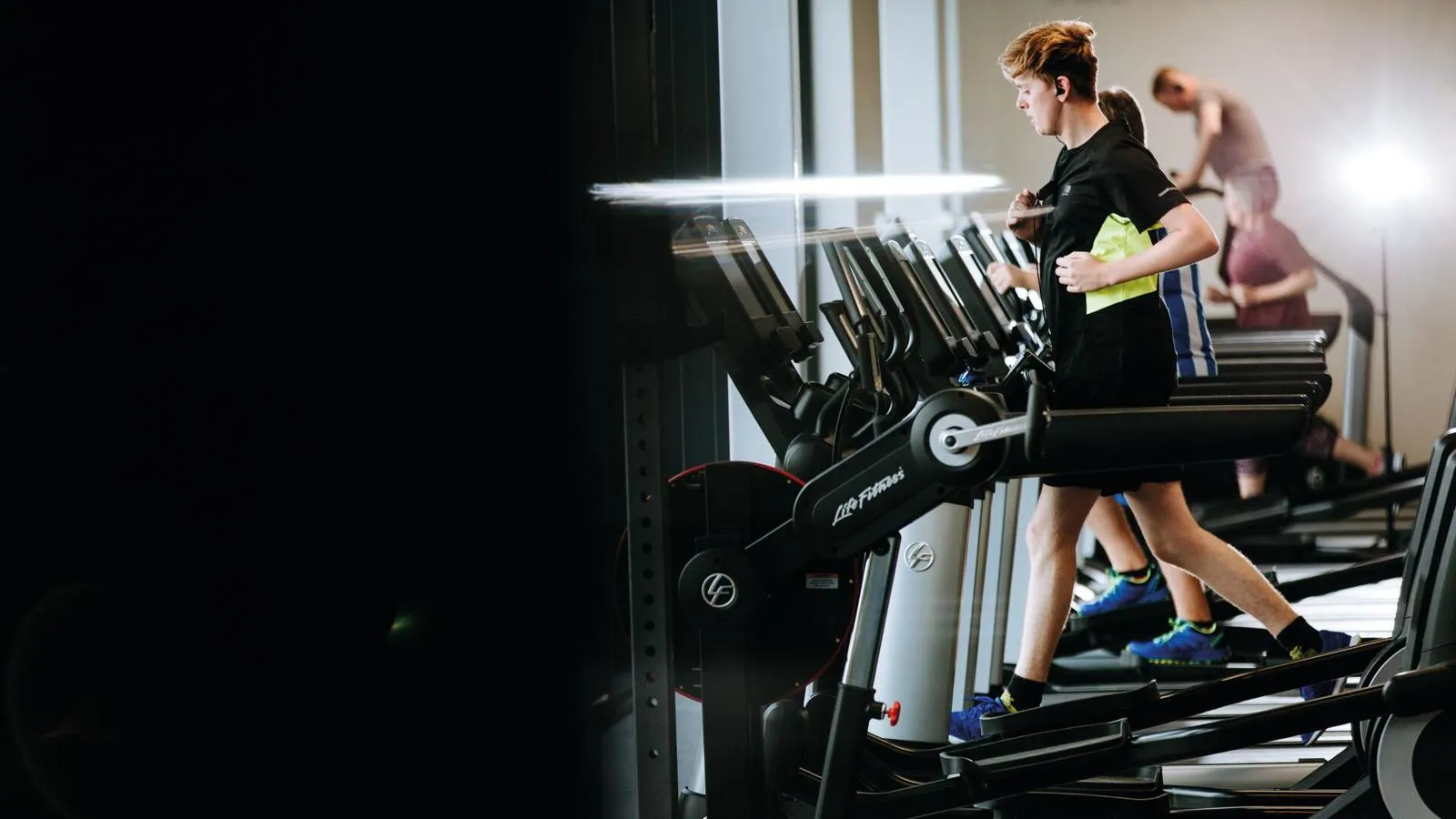 A row of treadmills with two students running on those furthest away