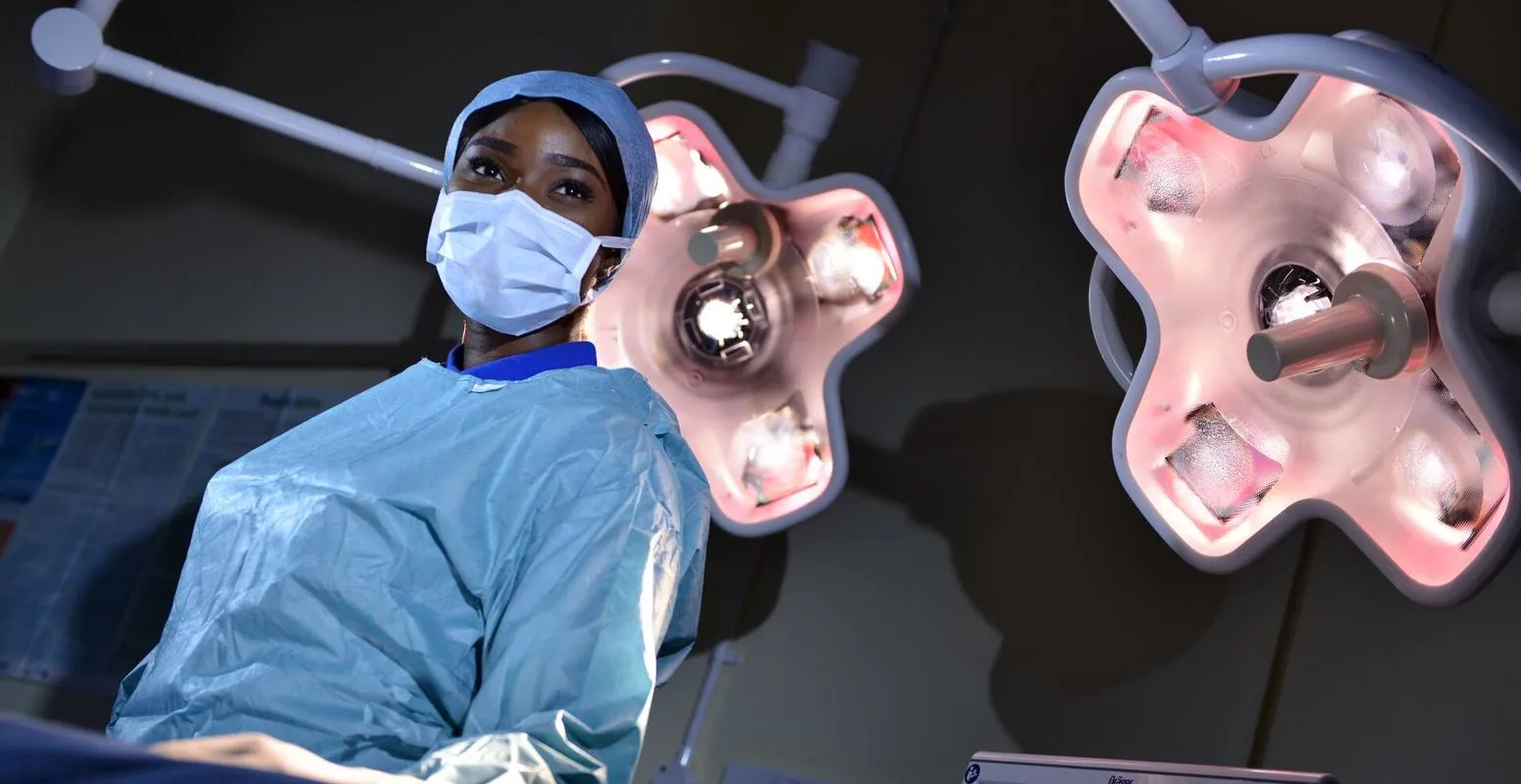 ODP student Olayemi Elizabeth Ajayi stands in scrubs at an operating table under the lights