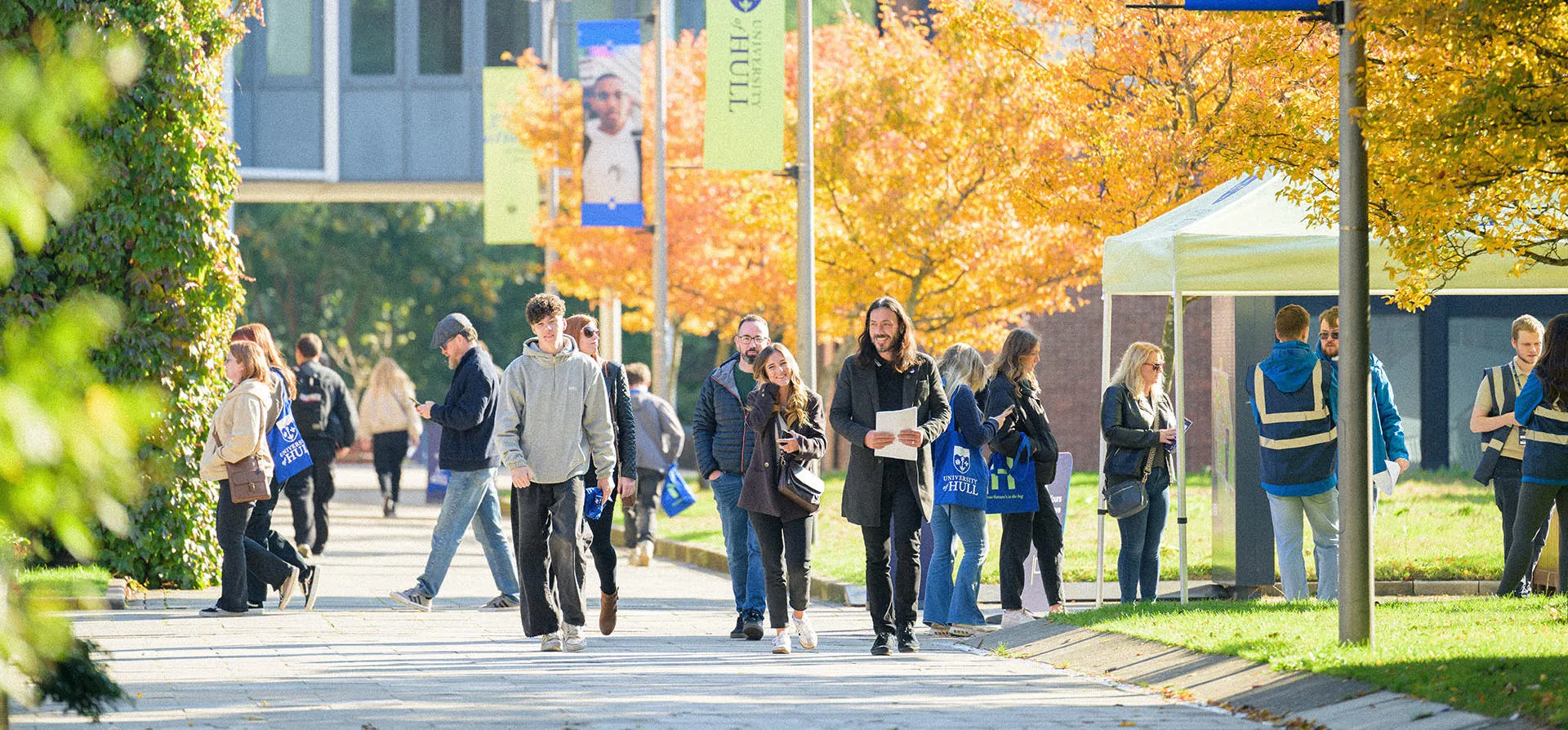 A large group of prospective students wandering campus on a sunny open day