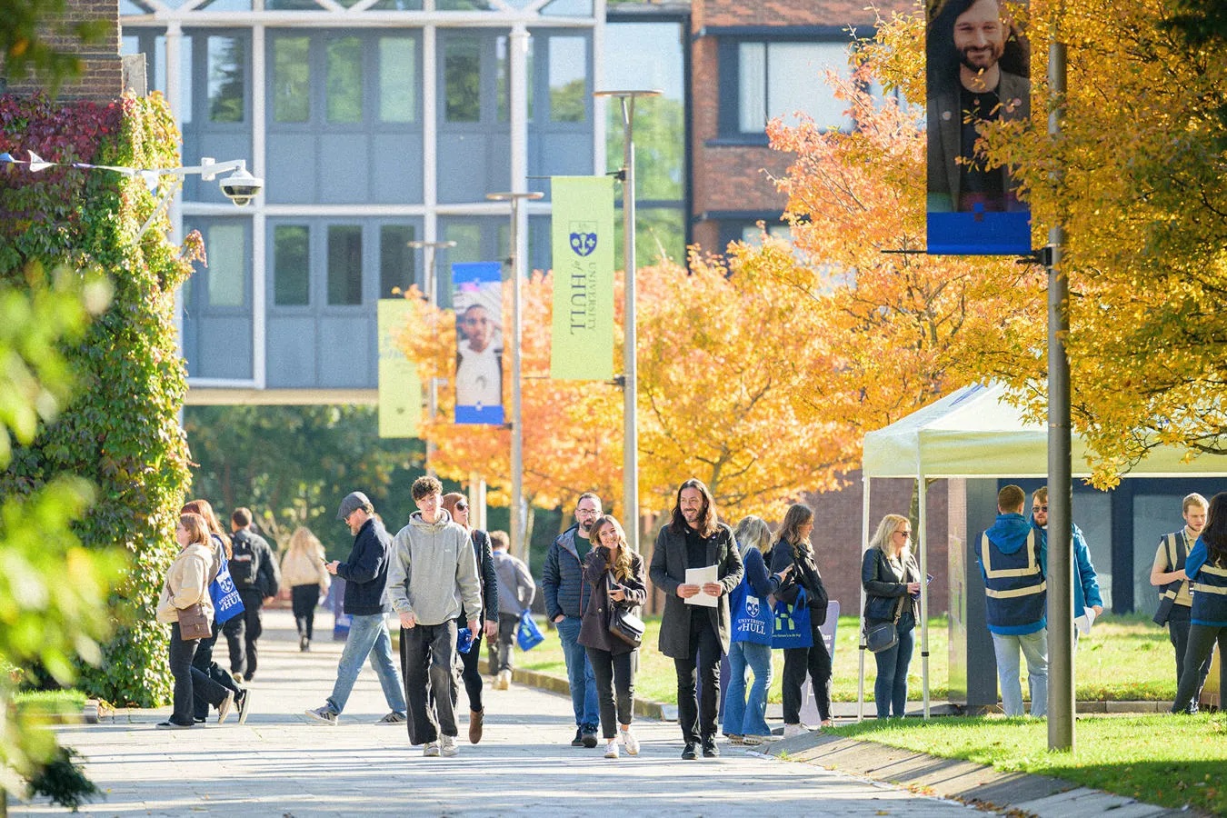 A large group of prospective students wandering campus on a sunny open day