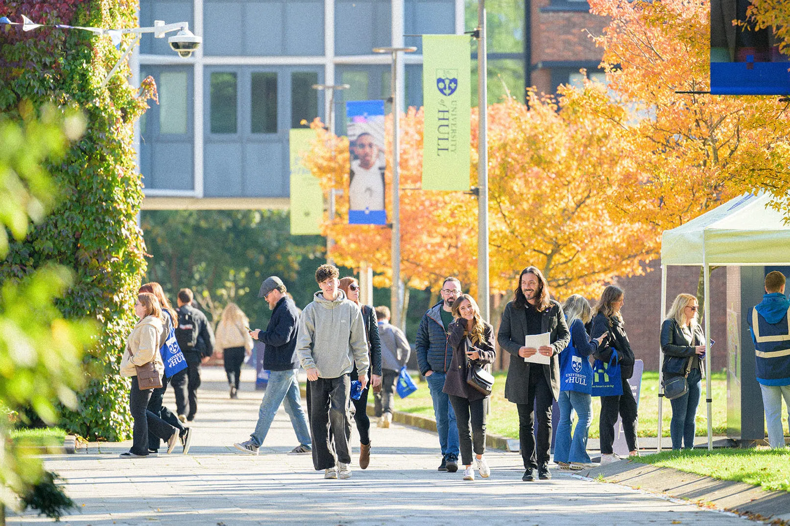 A large group of prospective students wandering campus on a sunny open day
