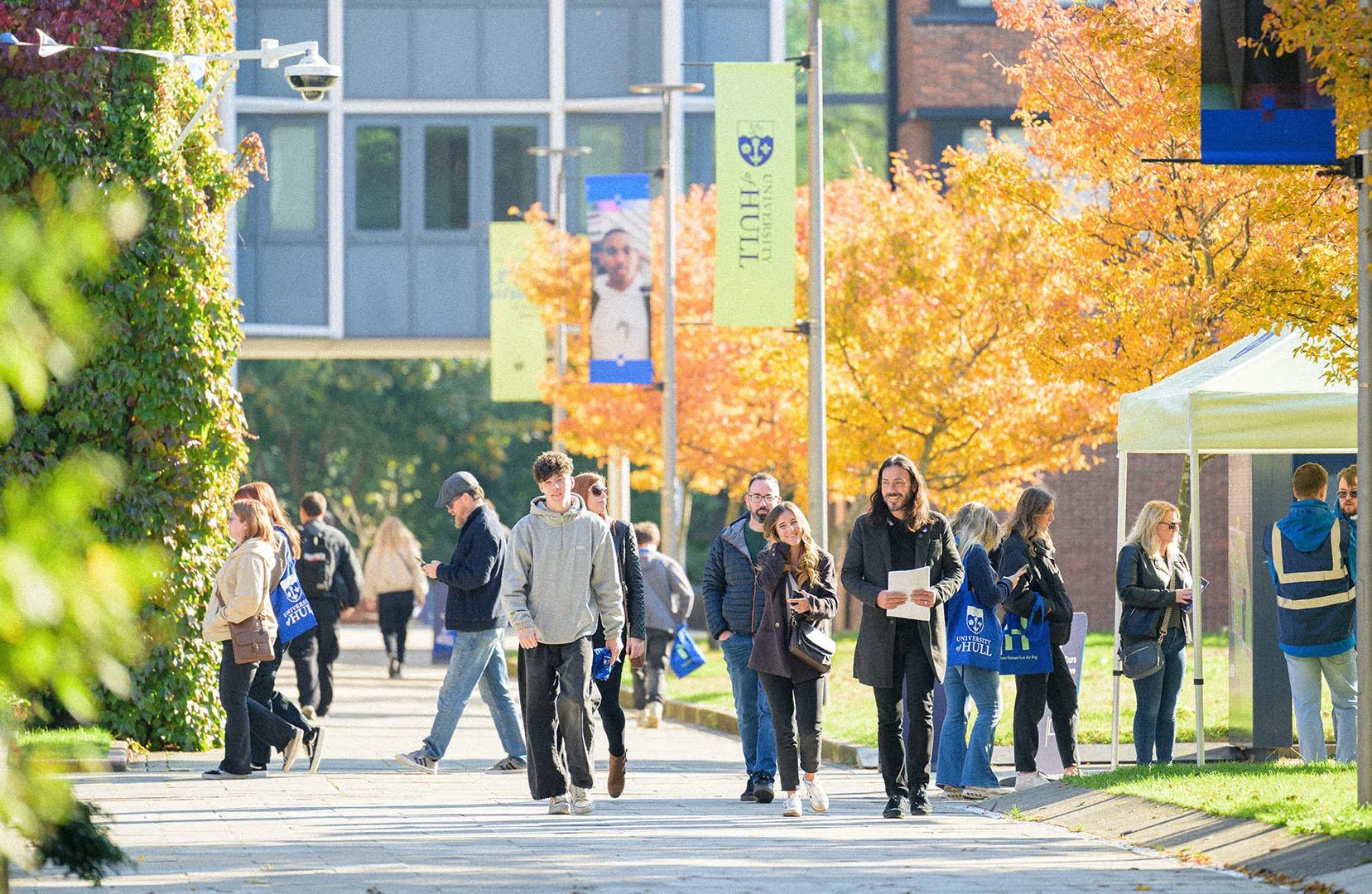 A large group of prospective students wandering campus on a sunny open day