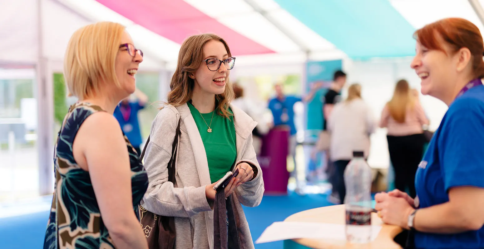 A student and their parent talking to a member of staff at an open day