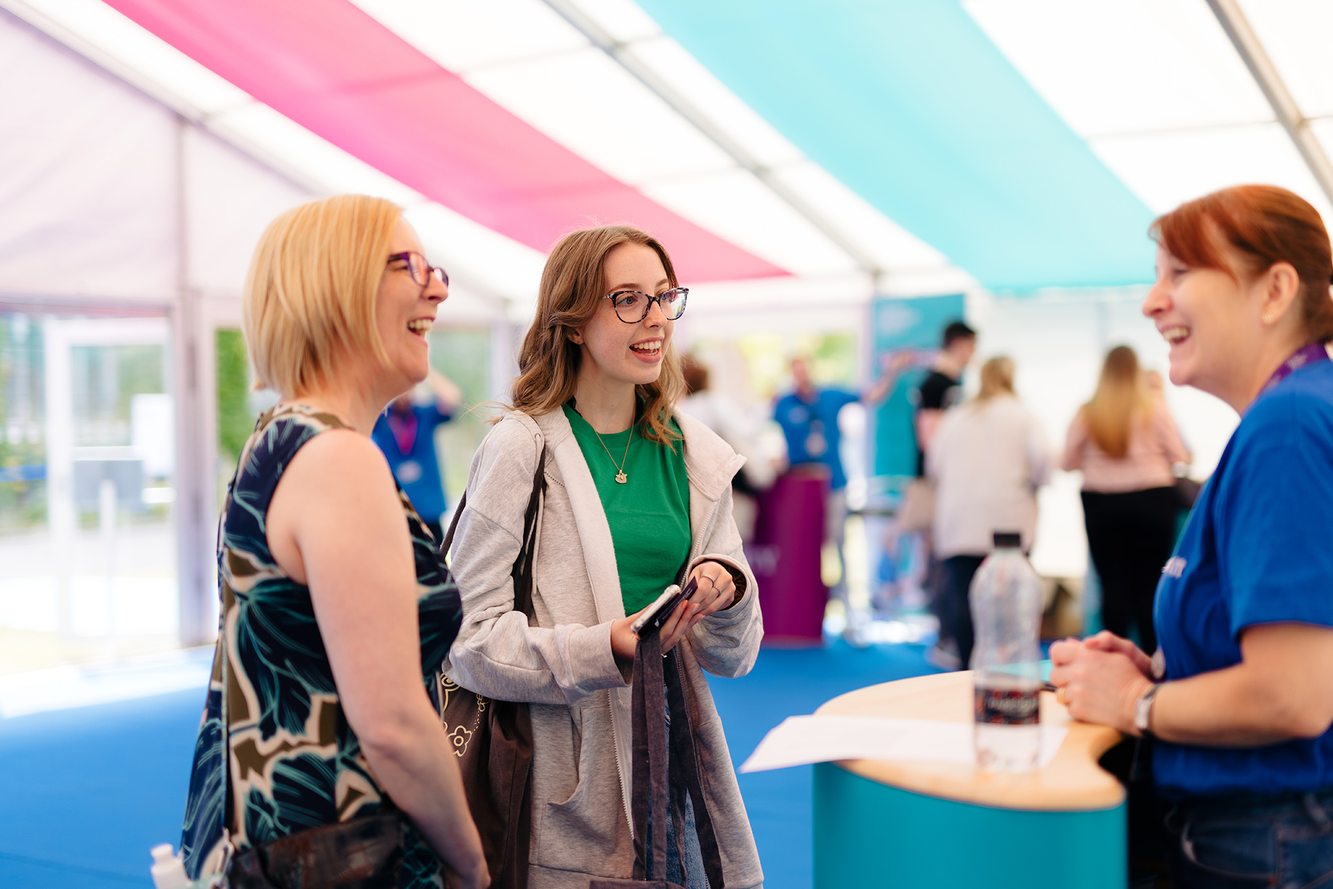 A student and their parent talking to a member of staff at an open day