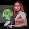Red haired female student holding VR headset standing in front of image of green skull