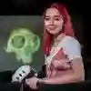 Red haired female student holding VR headset standing in front of image of green skull