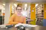 Student smiling on a table at the library