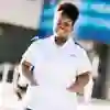 An Adult Nursing student in a white uniform standing in front of the university's health building on campus
