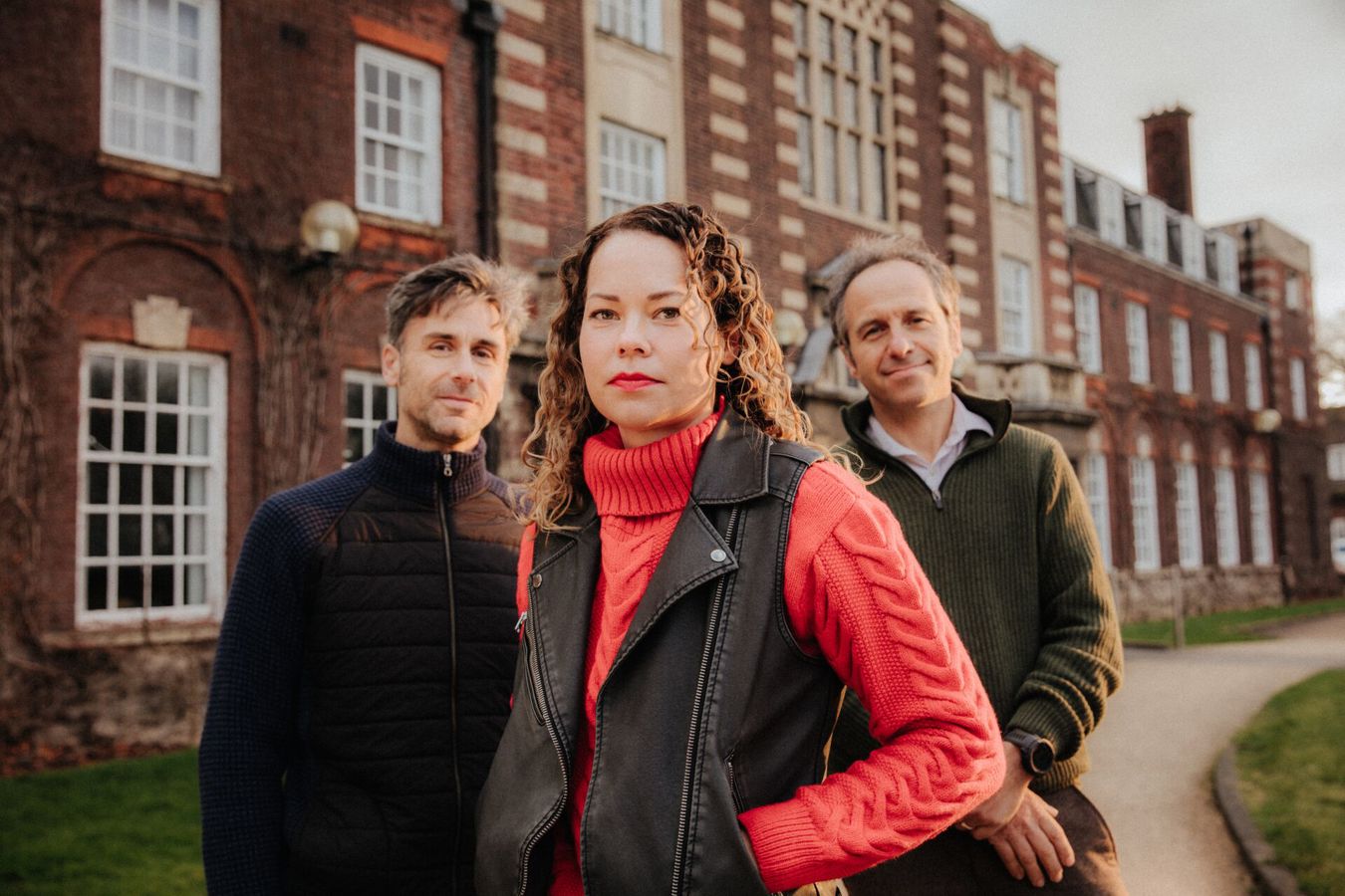 Three of Hull’s academics stand confidently together in front of an old red brick building