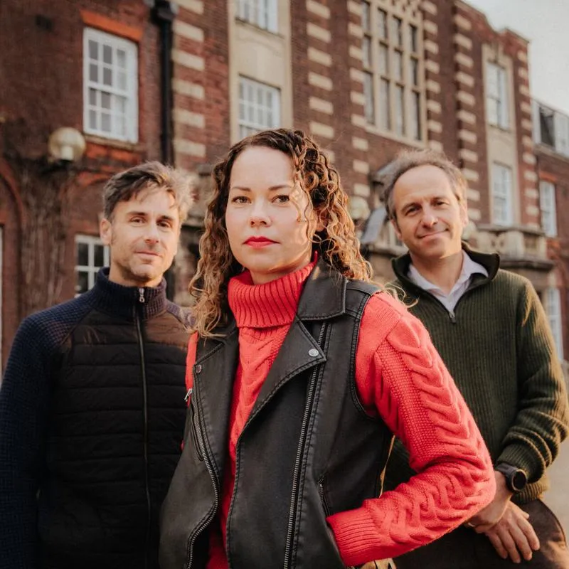 Three of Hull’s academics stand confidently together in front of an old red brick building
