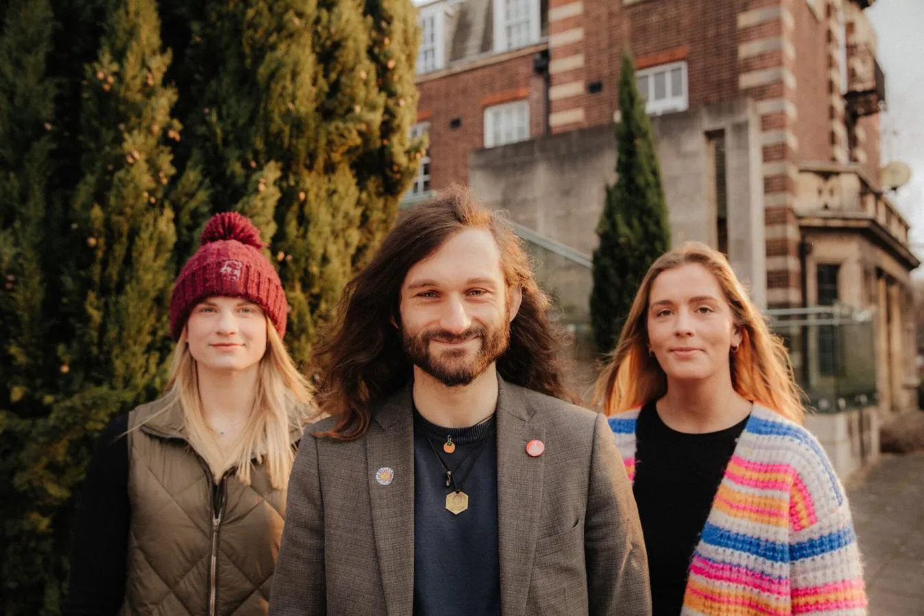 Three of Hull’s academics stand confidently together in front of a fern by the Business School's entrance