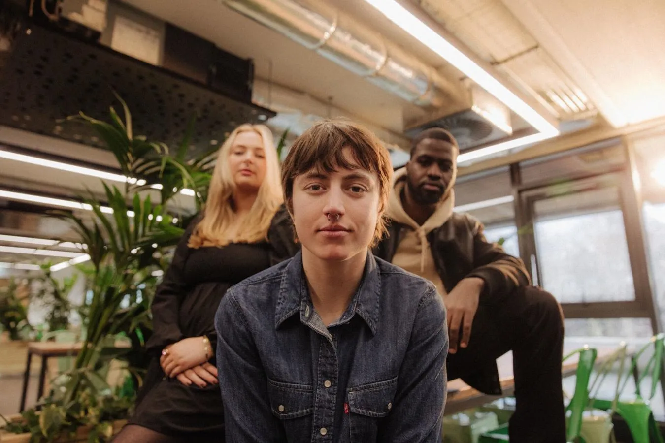 Three of Hull’s students sit confidently together in front of foliage in student hangout The Nest
