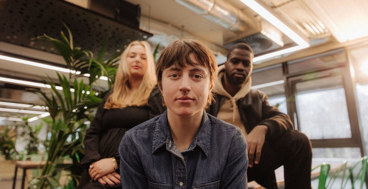 Three of Hull’s students sit confidently together in front of foliage in student hangout The Nest