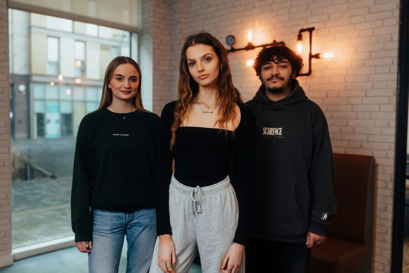Three of Hull’s students stand confidently together under warm lighting in our student accommodation