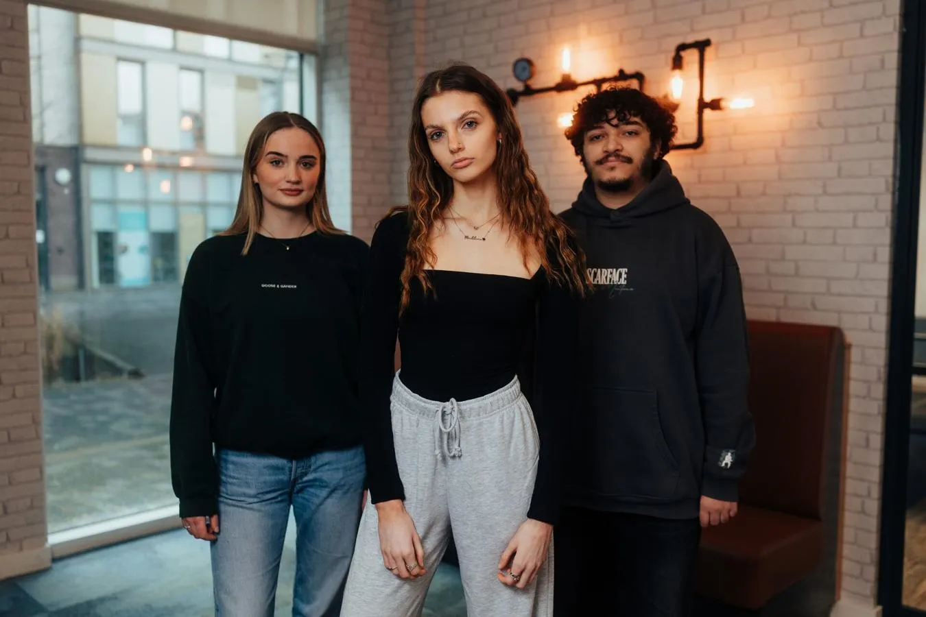 Three of Hull’s students stand confidently together under warm lighting in our student accommodation