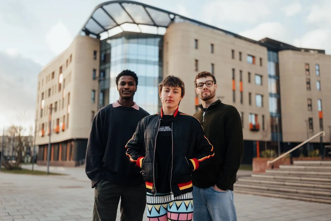 Three of Hull’s students stand confidently together in front of the modern Allam Medical Building
