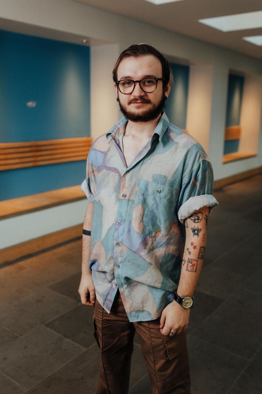 Three of Hull’s students stand confidently together in front of blue walls and wood panelled seating