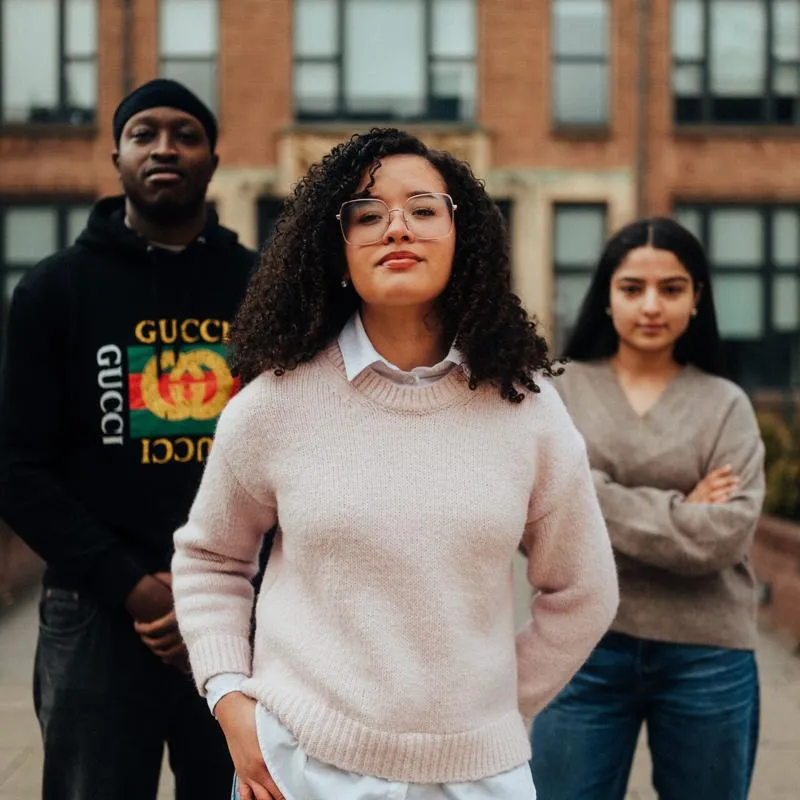 Three of Hull’s students stand confidently together in front of an ornate entrance to the Library