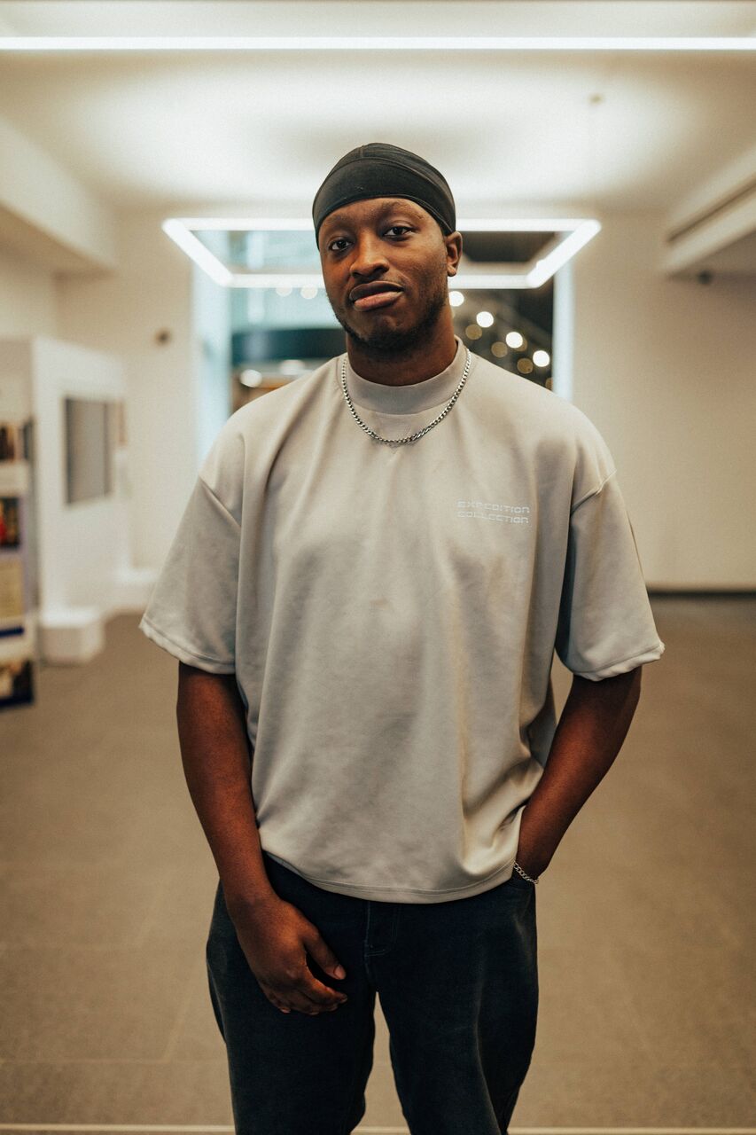 A male student  stands confidently under modern lighting in the Library's foyer