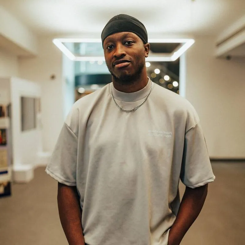 A male student stands confidently under modern lighting in the Library's foyer