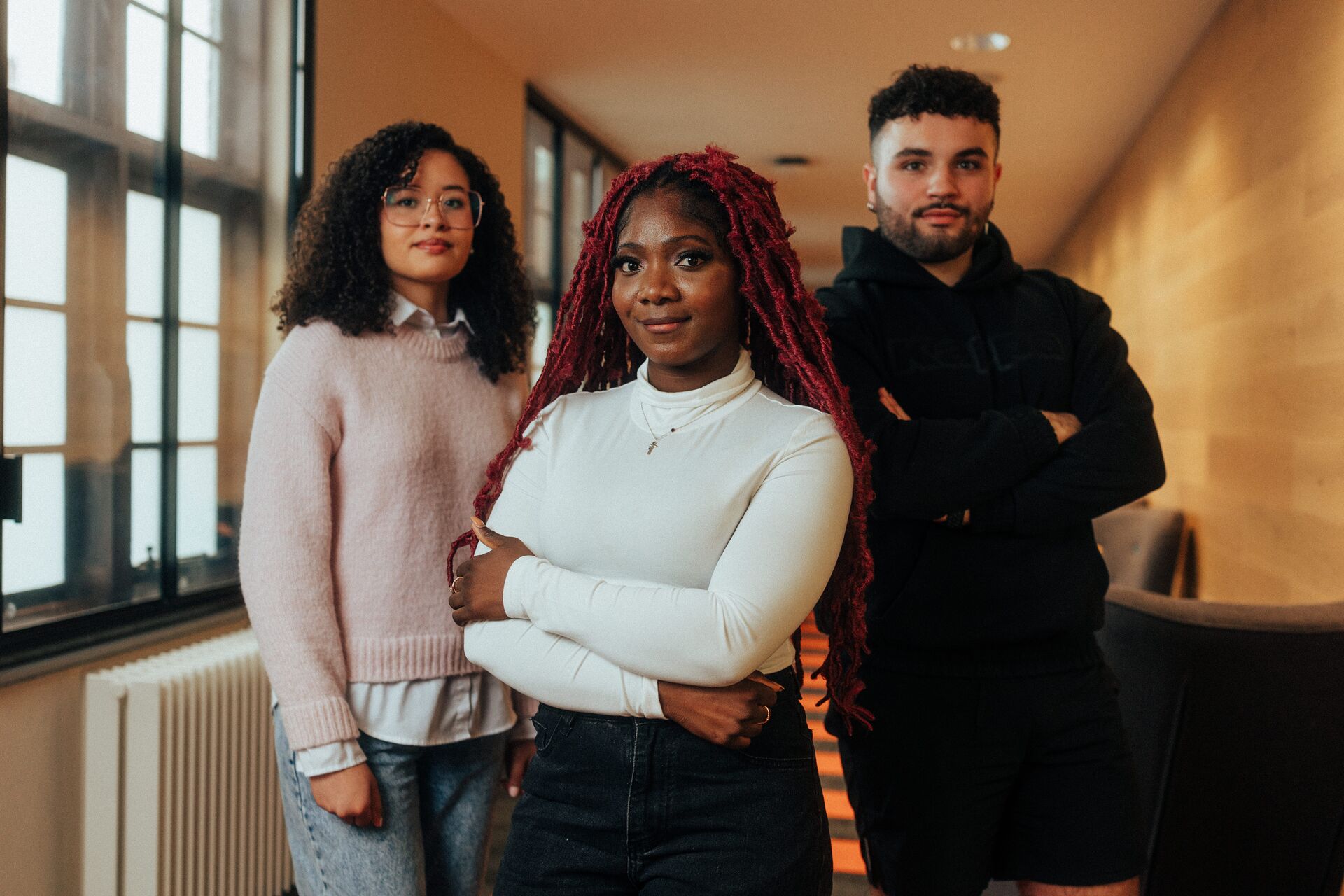 Three of Hull’s students stand confidently together in a modern corridor with wood panelling