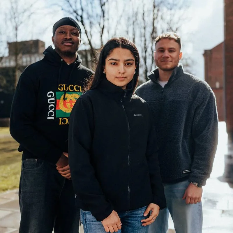 Three of Hull’s students stand confidently together on one of the campus' main walkways