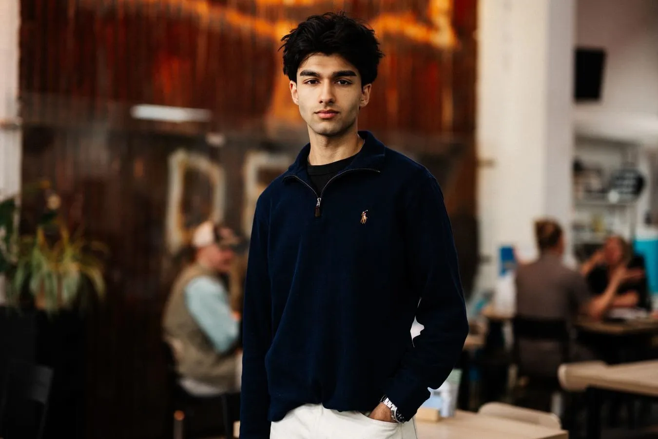 A male student in white jeans stands confidently in front of a rusted panel with Hull's iconic 'Dead Bod' artwork