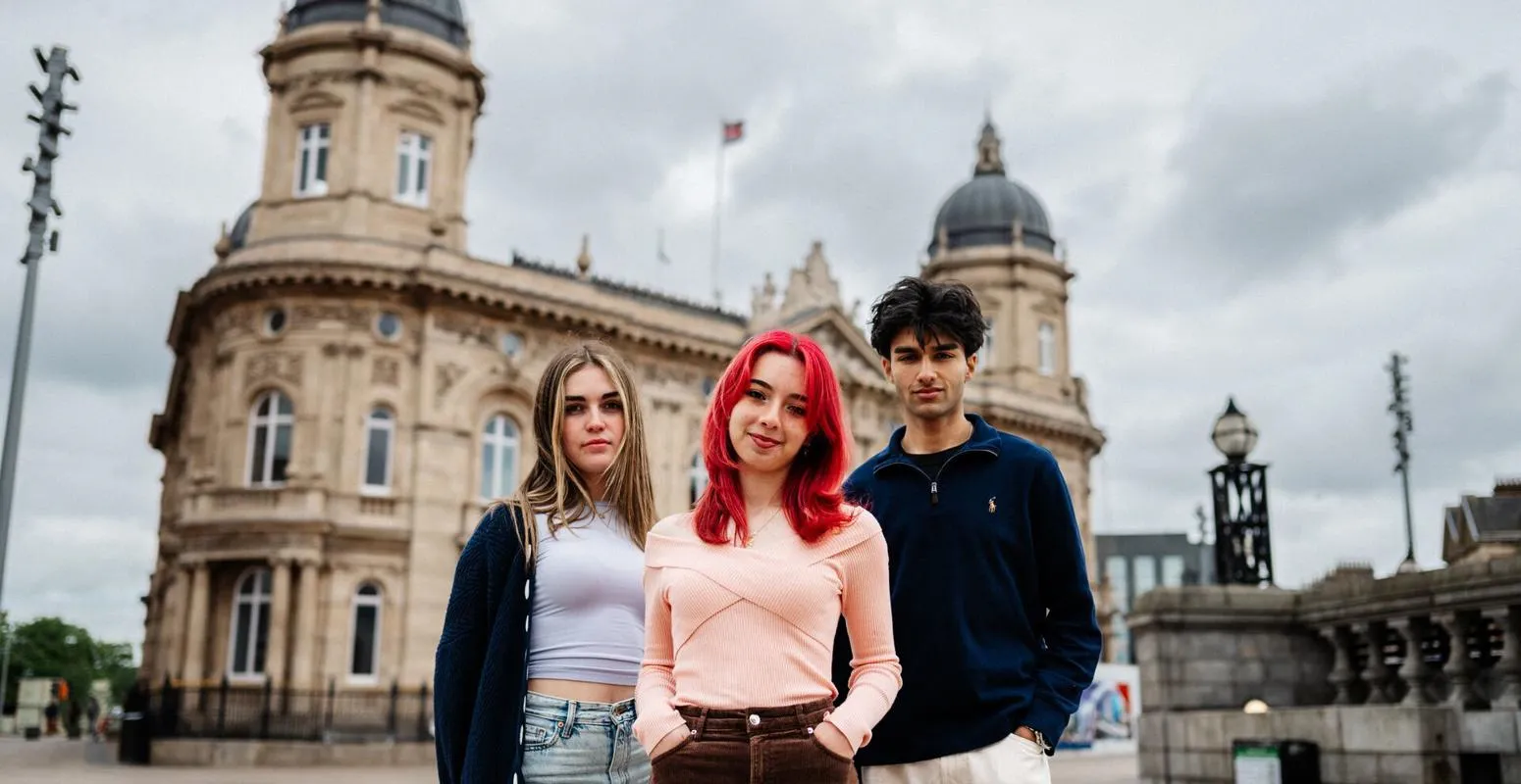 Three of Hull’s students stand confidently together in front of the Maritime Museum