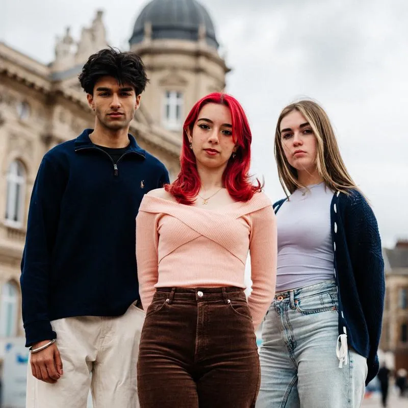 Three of Hull’s students stand confidently together in front of the Maritime Museum