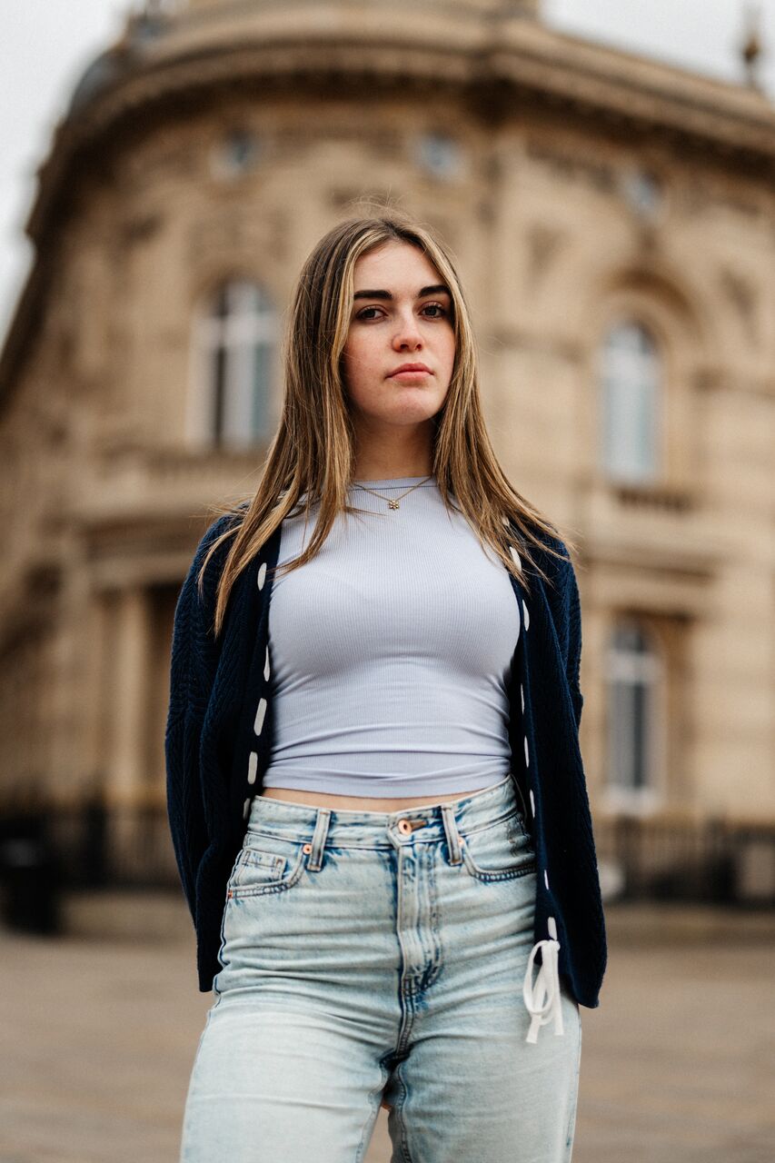 A female student in grey top stands confidently in front of the Maritime Museum