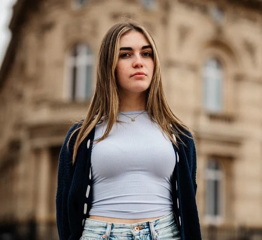 A female student in grey top stands confidently in front of the Maritime Museum
