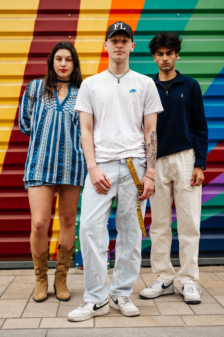 Three of Hull’s students stand confidently together in front of a bright mural painted on shutters