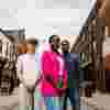 Three of Hull’s students stand confidently together under string lights on Humber Street