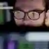 Man with glasses looks intently at a computer screen