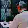 ICT technician wearing headphones running diagnostics on a laptop in front of a large server