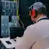 ICT technician wearing headphones running diagnostics on a laptop in front of a large server