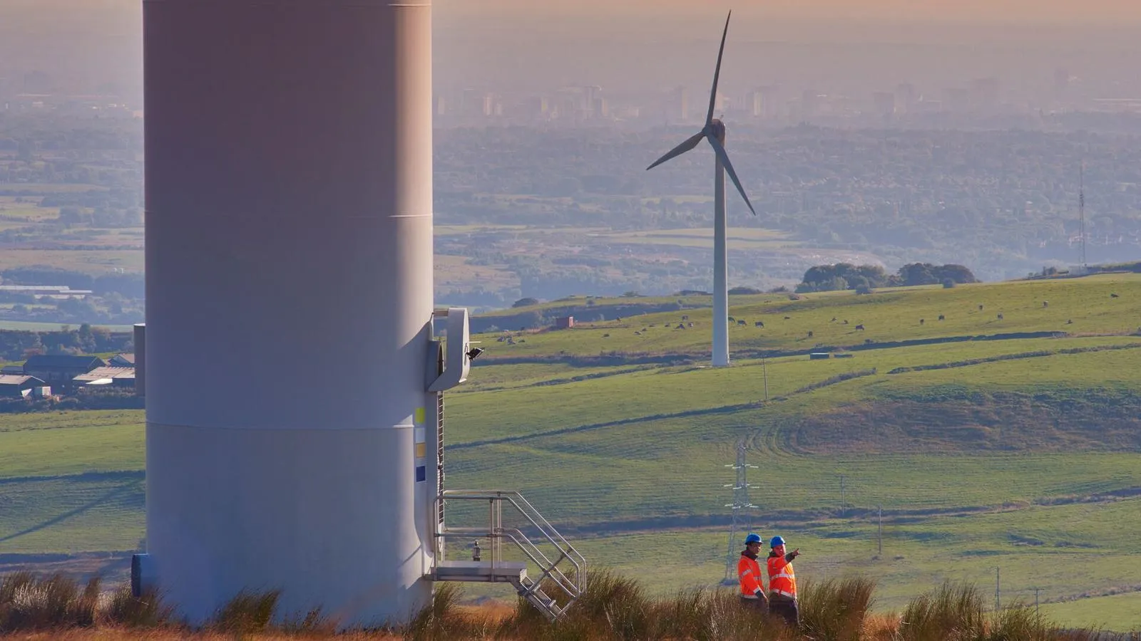 Wind turbines and workers in a green field