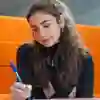 Student sat in a booth writing on paper
