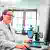 A researcher in a lab coat on a computer