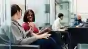 two students on chairs in business lounge chatting
