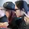 Two students sat at a desk on their phones