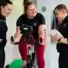 Three sports students, one on an exercise bike whilst the others monitor their progress